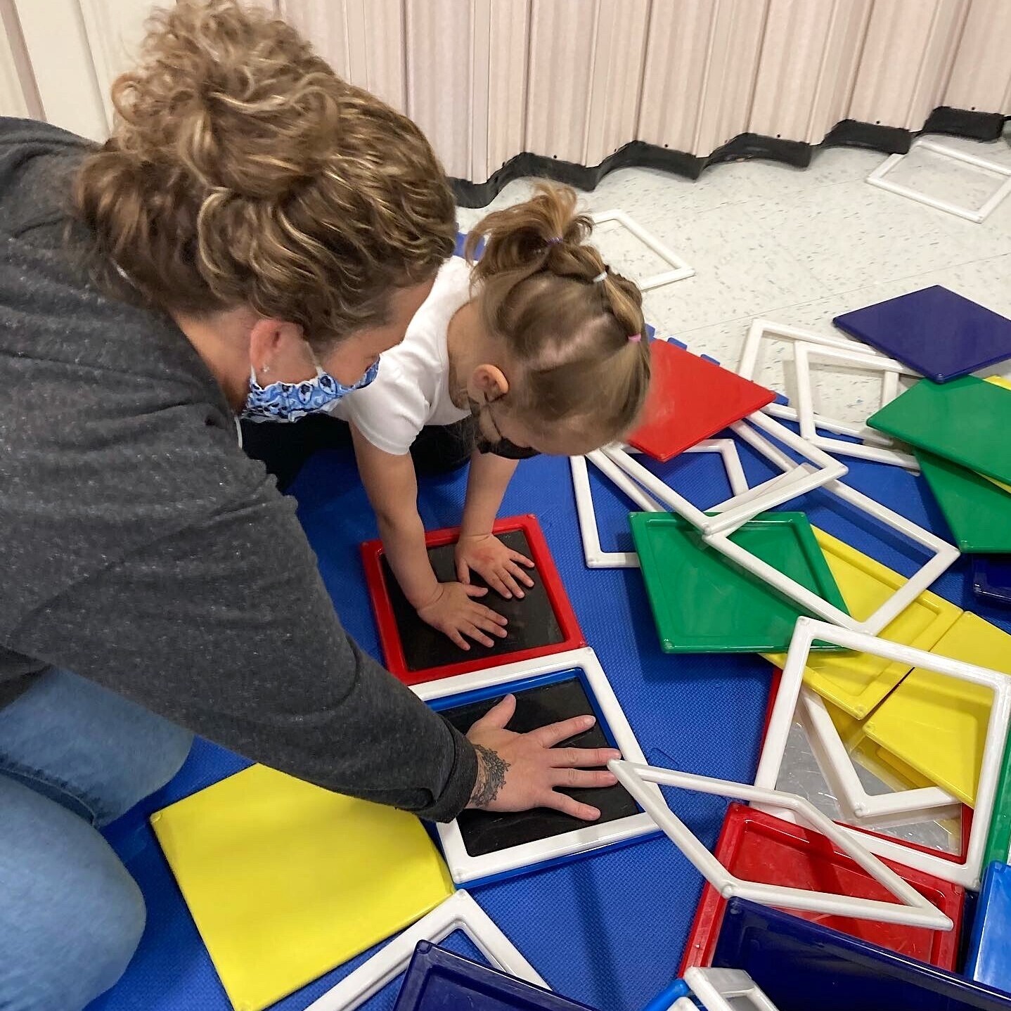 Adult and child placing hands on square toys